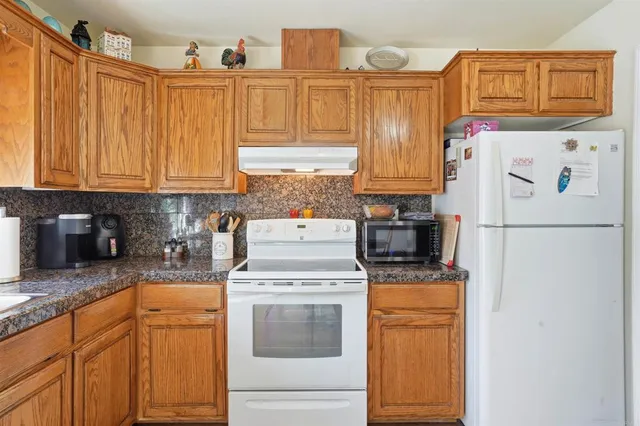 a kitchen with stainless steel appliances granite countertop a refrigerator a stove and a sink