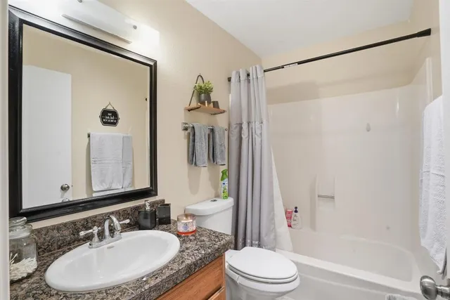 a bathroom with a granite countertop sink toilet and shower