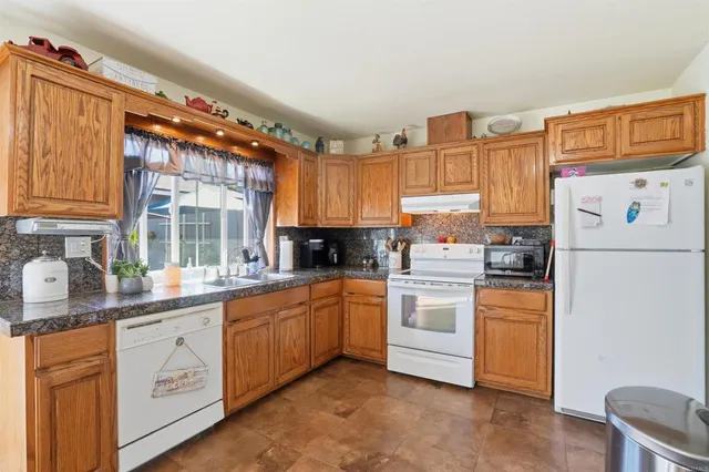 a kitchen with stainless steel appliances granite countertop a refrigerator a stove a sink and white cabinets
