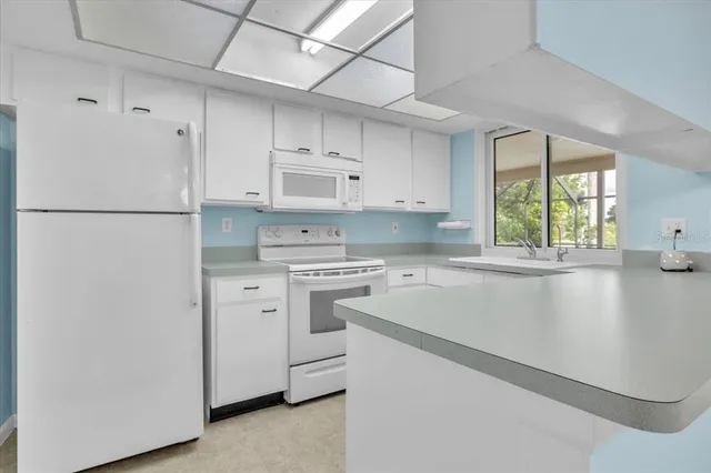 a kitchen with white cabinets and white appliances