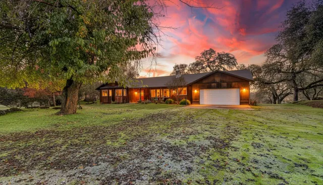 a front view of house with yard and trees all around