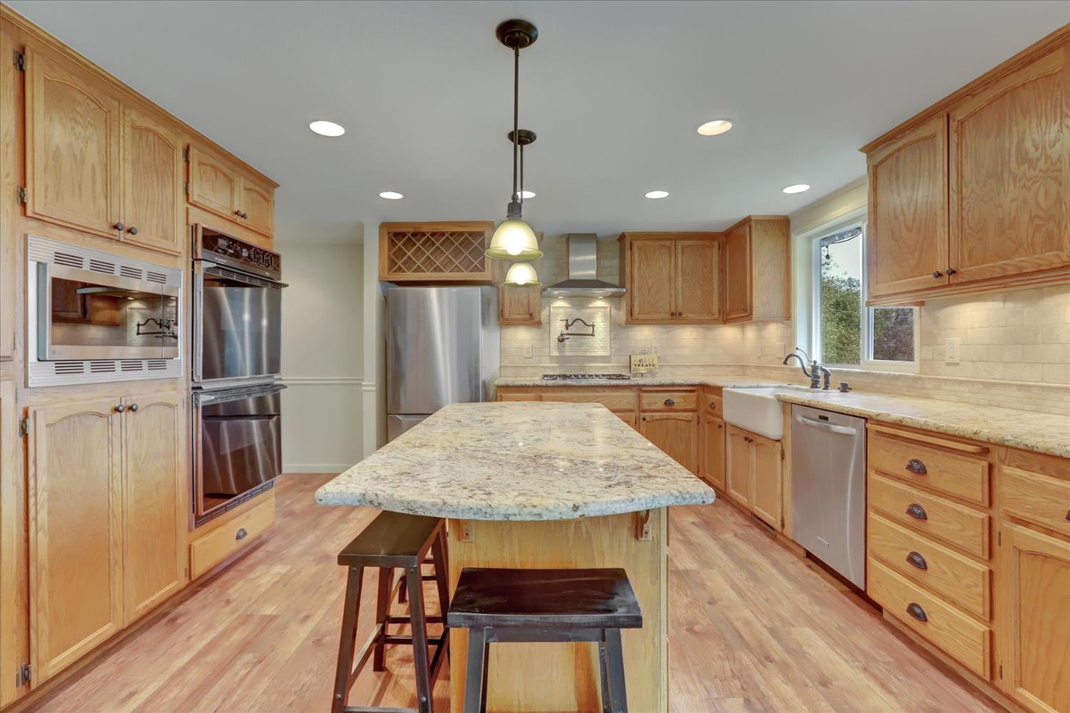 19310 John Born Road Penn Valley, CA 95946 - Photo 6 of 78 a kitchen with stainless steel appliances granite countertop sink refrigerator dining table and chairs