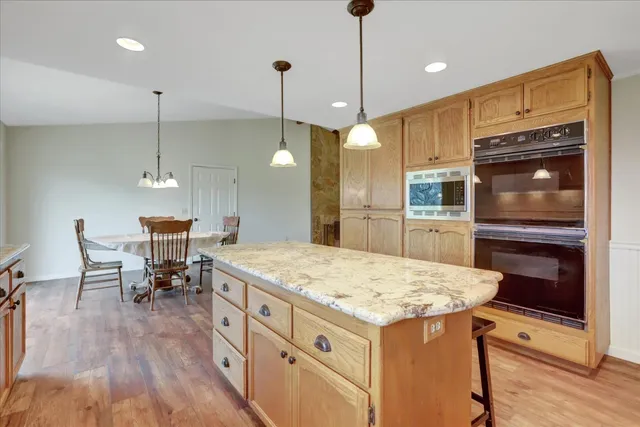 an empty room with a chandelier fan and wooden floor