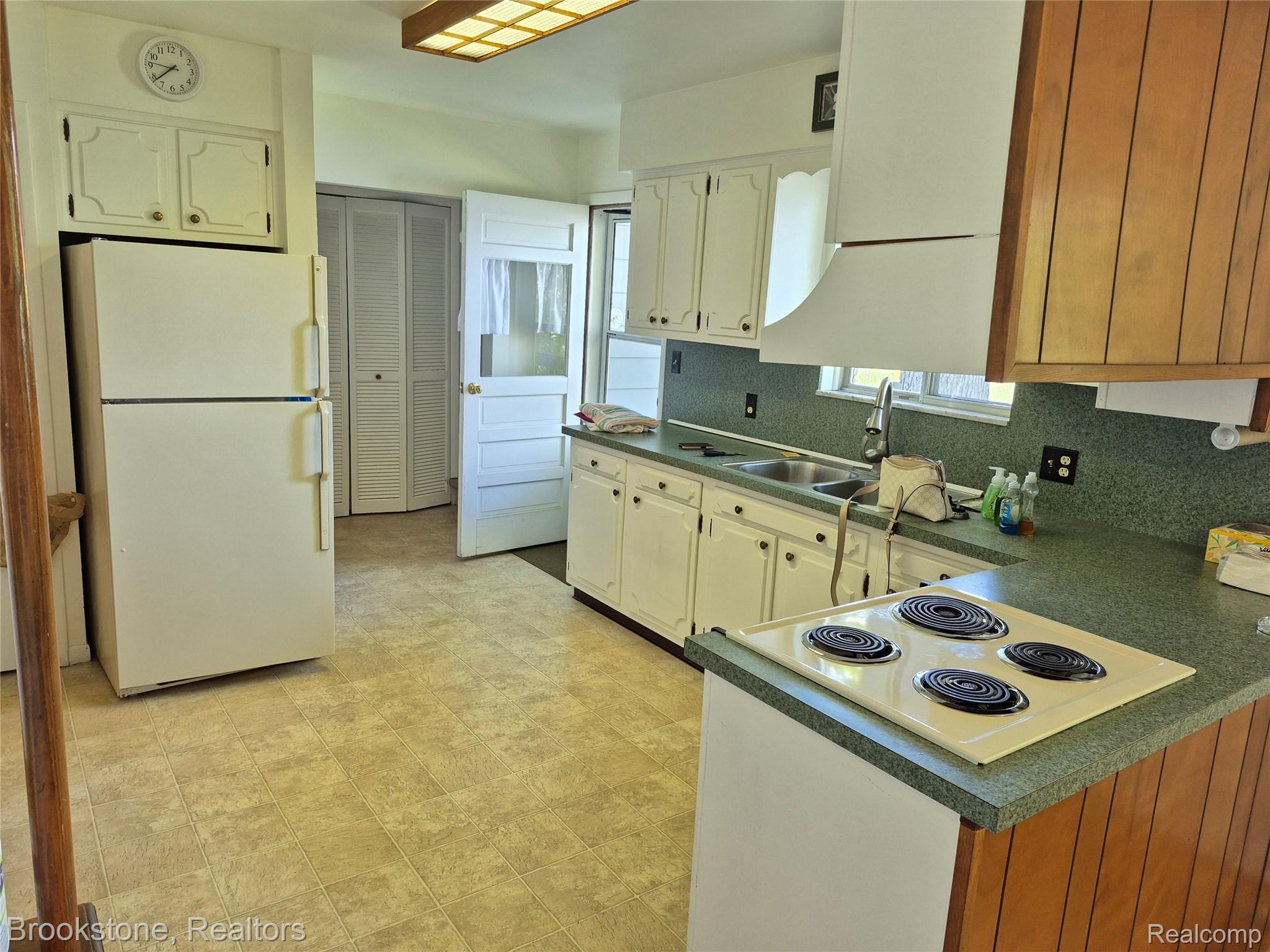 4295 Sashabaw Road Waterford, MI 48329 - Photo 14 of 37 Kitchen featuring a built-in electric cooktop, double basin sink, white cabinetry, and wood-finish paneling