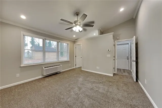 an empty room with chandelier fan and windows