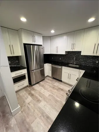 a kitchen with granite countertop a refrigerator and a sink