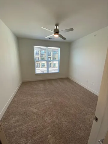 an empty room with a ceiling fan and window