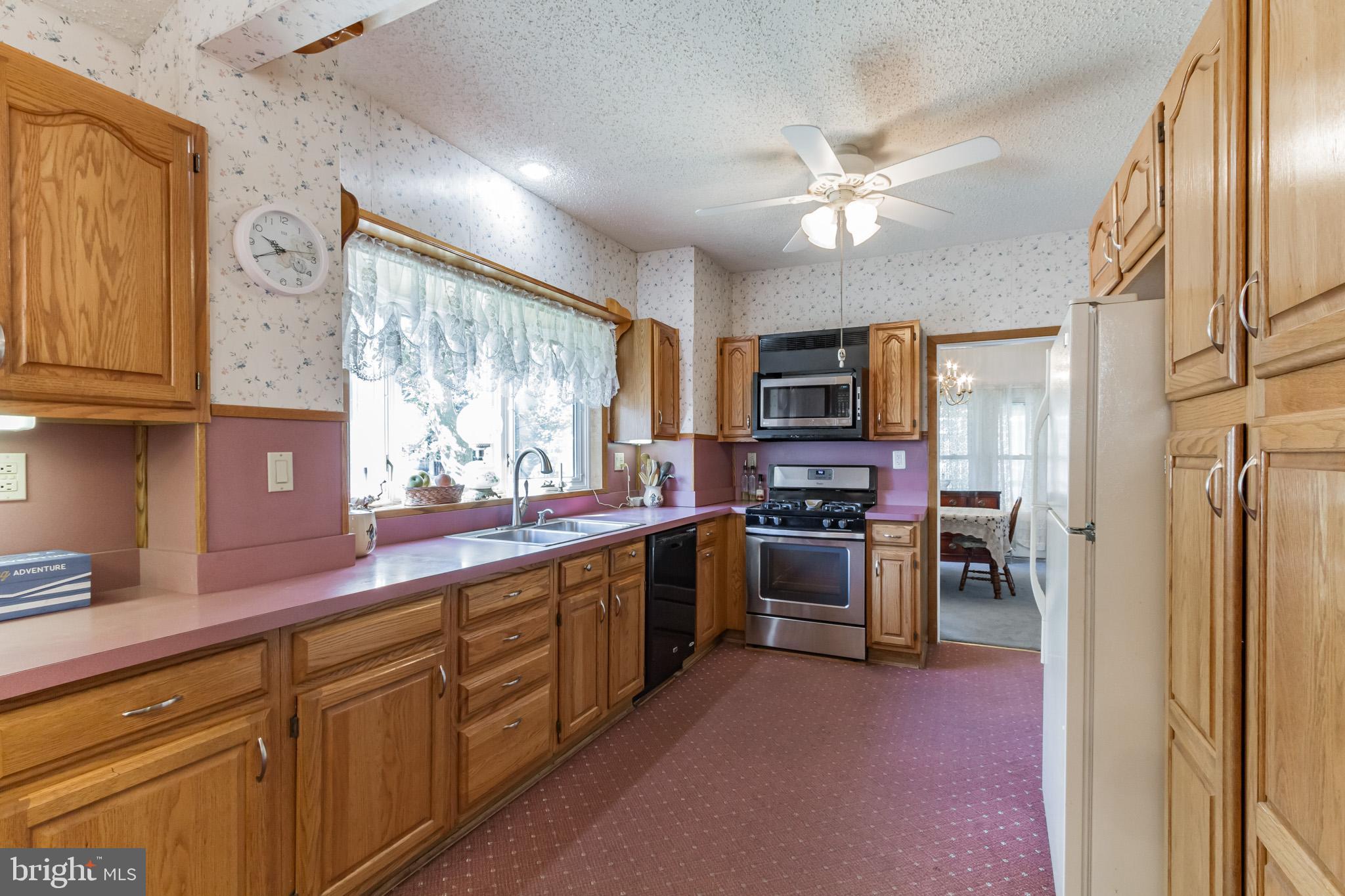 213 Garnet Street Carneys Point, NJ 08069 - Photo 12 of 39 a kitchen with stainless steel appliances granite countertop a refrigerator a sink dishwasher a stove with wooden cabinets and floor