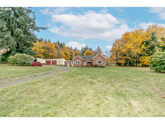 a view of house in front of a big yard with large trees
