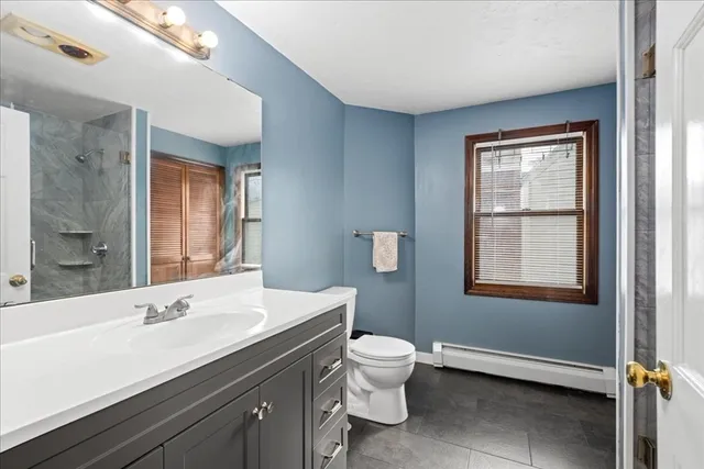 a bathroom with a sink toilet a mirror and window