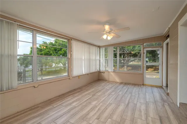 a view of empty room with wooden floor and fan