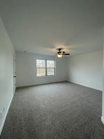 an empty room with a ceiling fan and windows