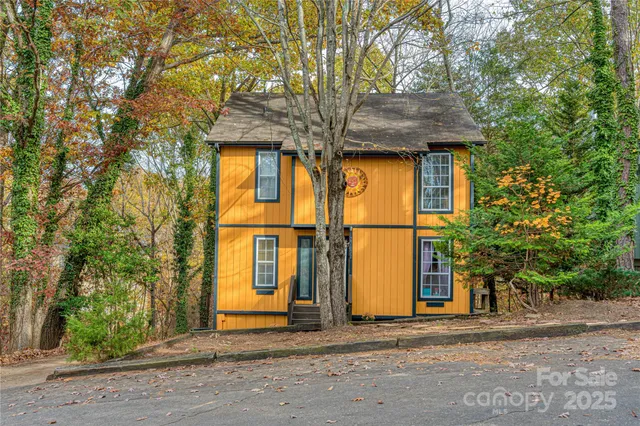 a view of a house with large tree and wooden fence