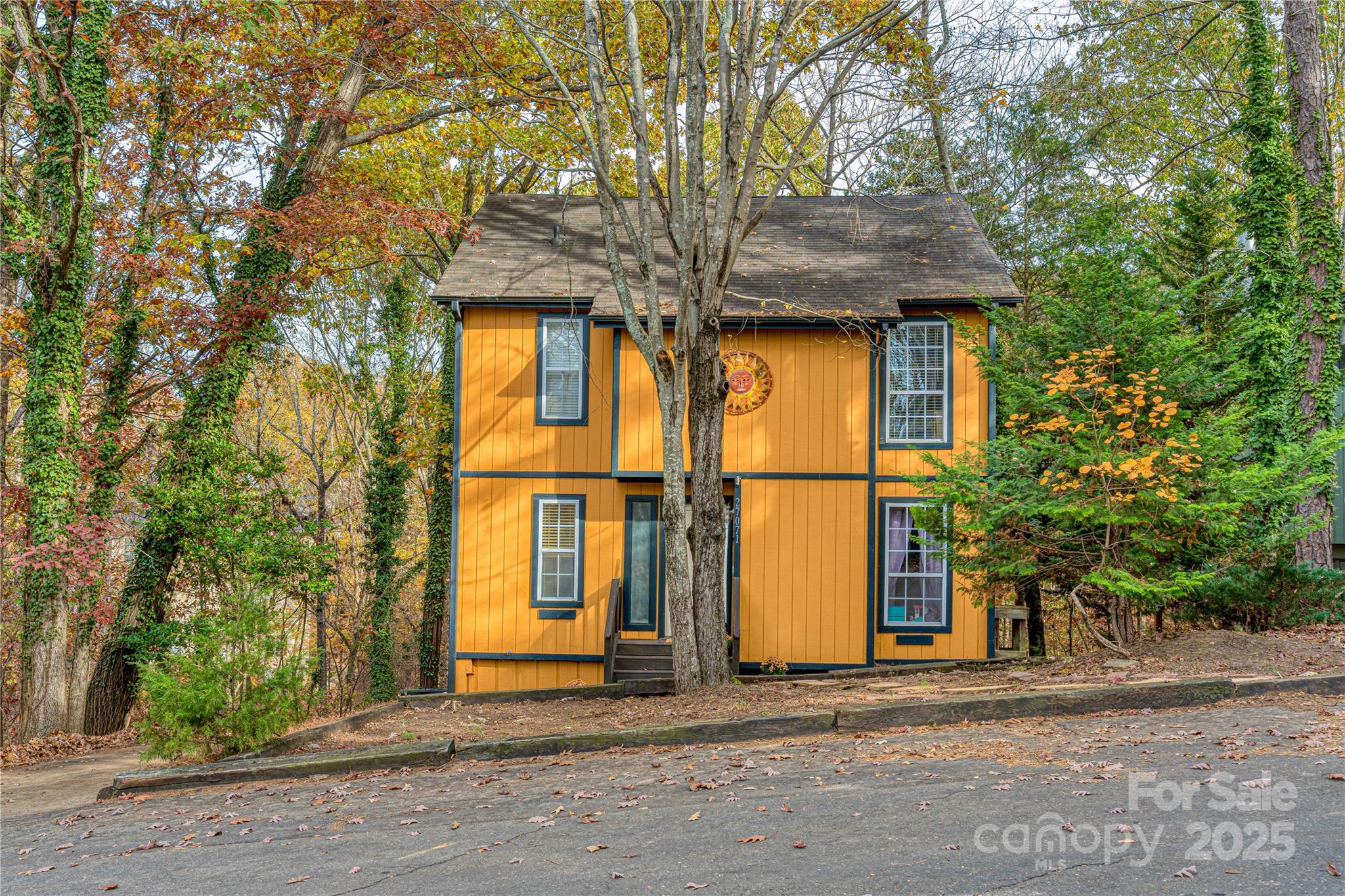 a view of a house with large tree and wooden fence