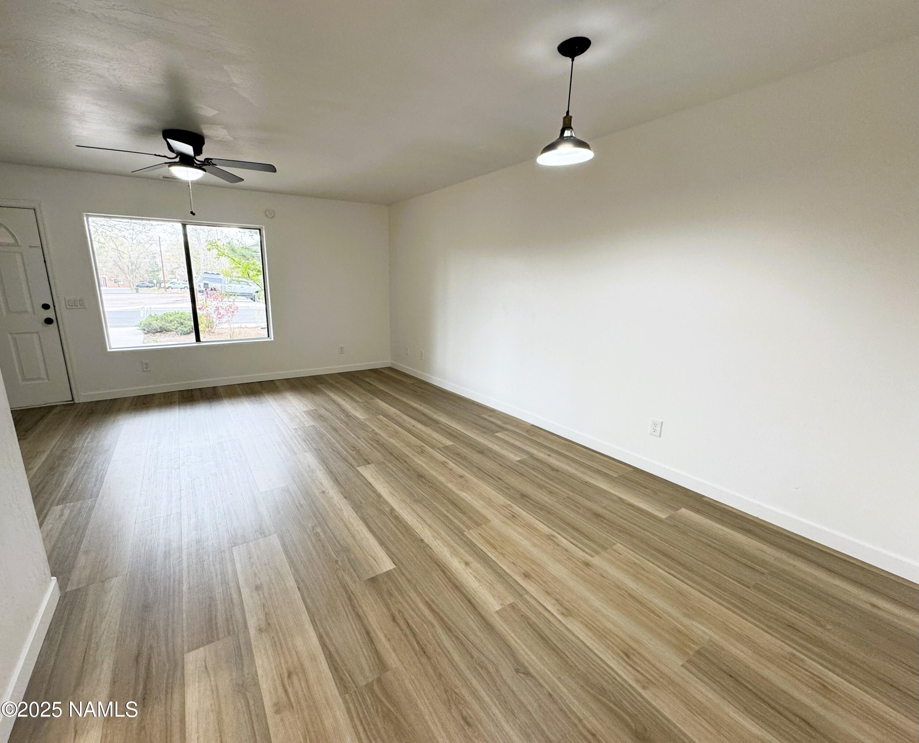 1807 North Main Street Flagstaff, AZ 86004 - Photo 6 of 26 an empty room with wooden floor chandelier fan and windows