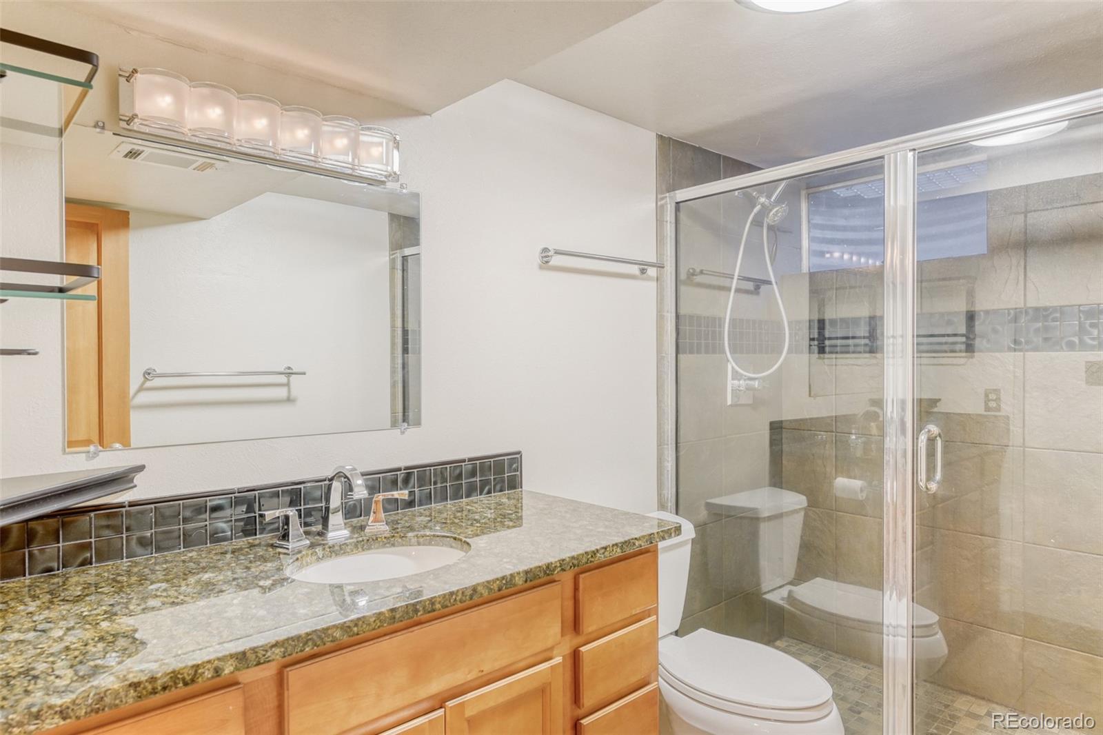 128 Olympus Circle Lone Tree, CO 80124 - Photo 9 of 35 a bathroom with a granite countertop sink toilet a mirror and shower