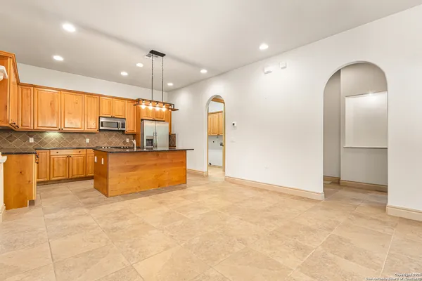 a large kitchen with kitchen island granite countertop a stove a sink a refrigerator and blue cabinets