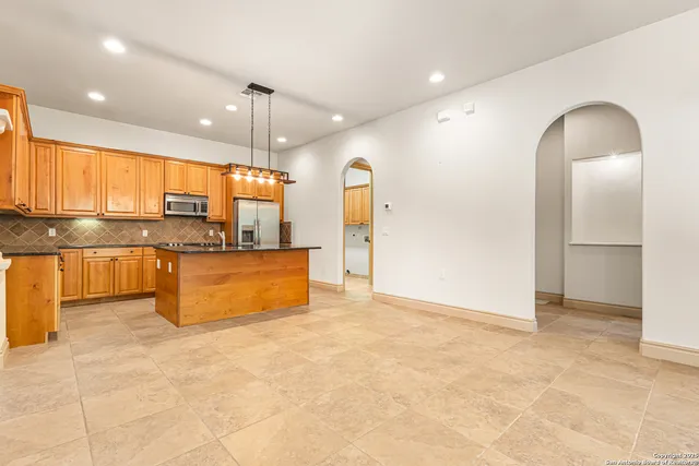 a large kitchen with kitchen island granite countertop a stove a sink a refrigerator and blue cabinets