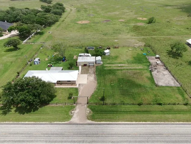an aerial view of residential houses with outdoor space and trees