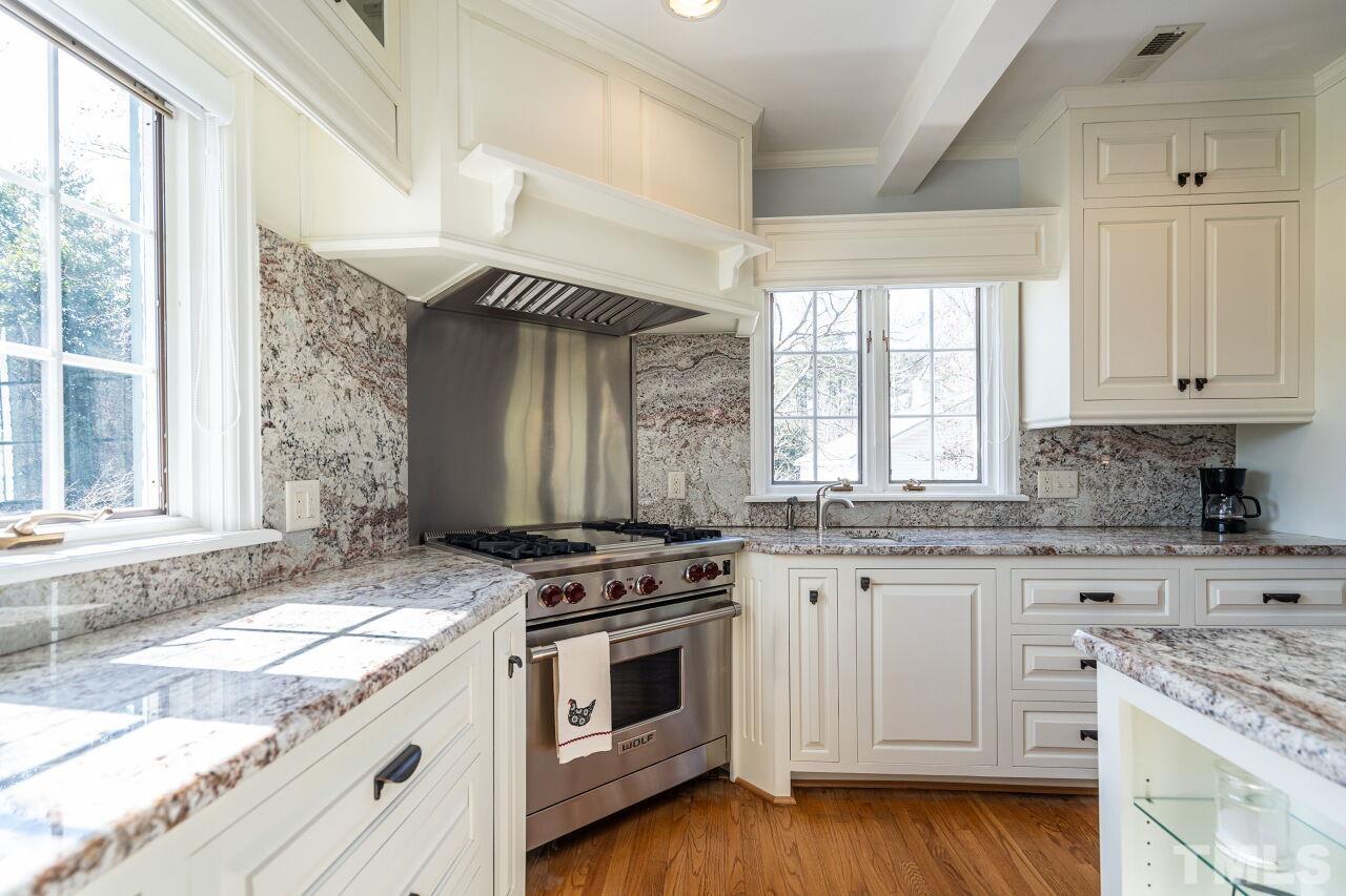 5212 Theys Road Raleigh, NC 27606 - Photo 27 of 55 a kitchen with granite countertop a stove a sink and cabinetry