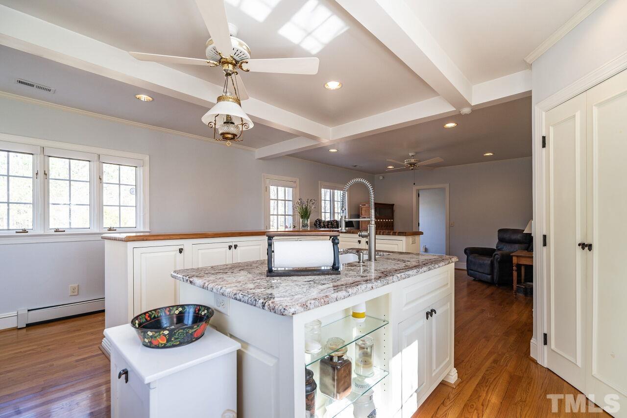 5212 Theys Road Raleigh, NC 27606 - Photo 28 of 55 a kitchen with granite countertop cabinets a dining table and chairs with wooden floor