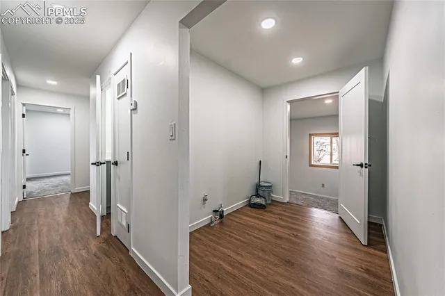 a view of a hallway with wooden floor and a bathroom