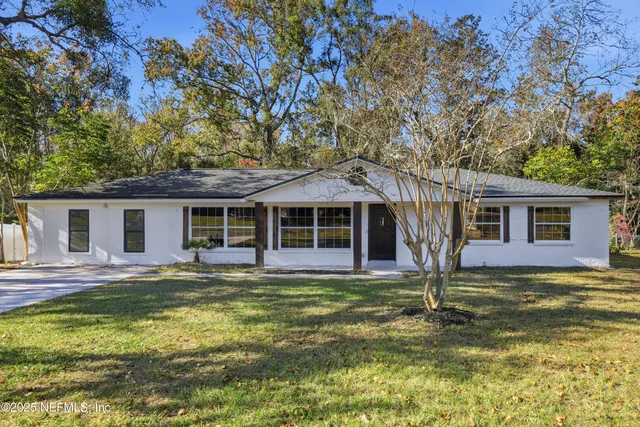 a view of an empty room with wooden floor and a kitchen