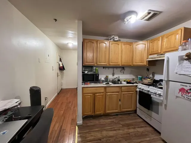 a kitchen with cabinets appliances wooden floor and a window
