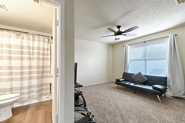 a bathroom with a granite countertop toilet a sink a mirror and shower curtain