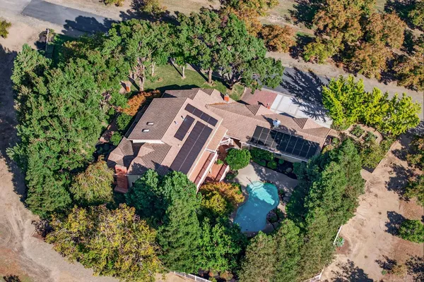 an aerial view of a house with a yard and trees all around