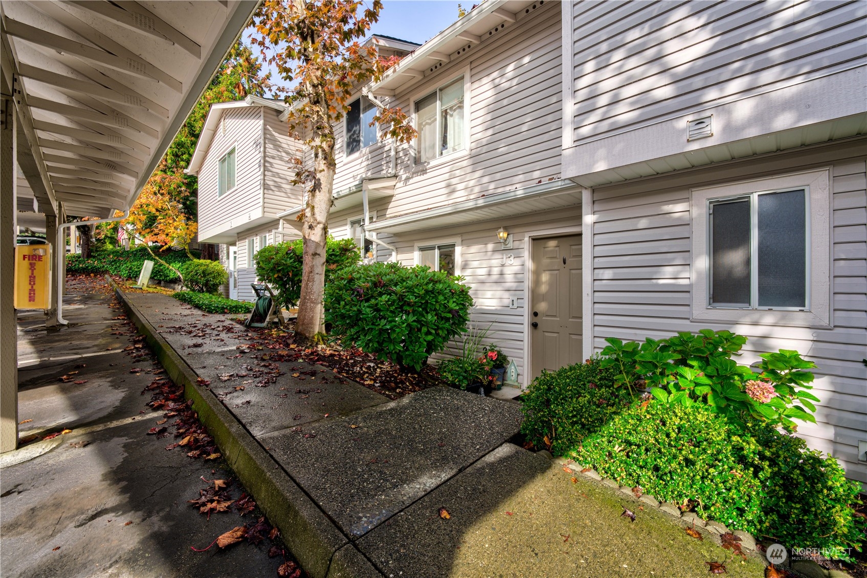 18910 Bothell Everett Highway, Unit J3 Bothell, WA 98012 - Photo 3 of 33 a view of a house with brick walls plants and large tree