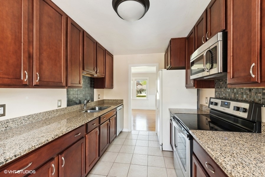 605 Revere Road Glenview, IL 60025 - Photo 4 of 18 a kitchen with stainless steel appliances granite countertop a stove a sink and a microwave
