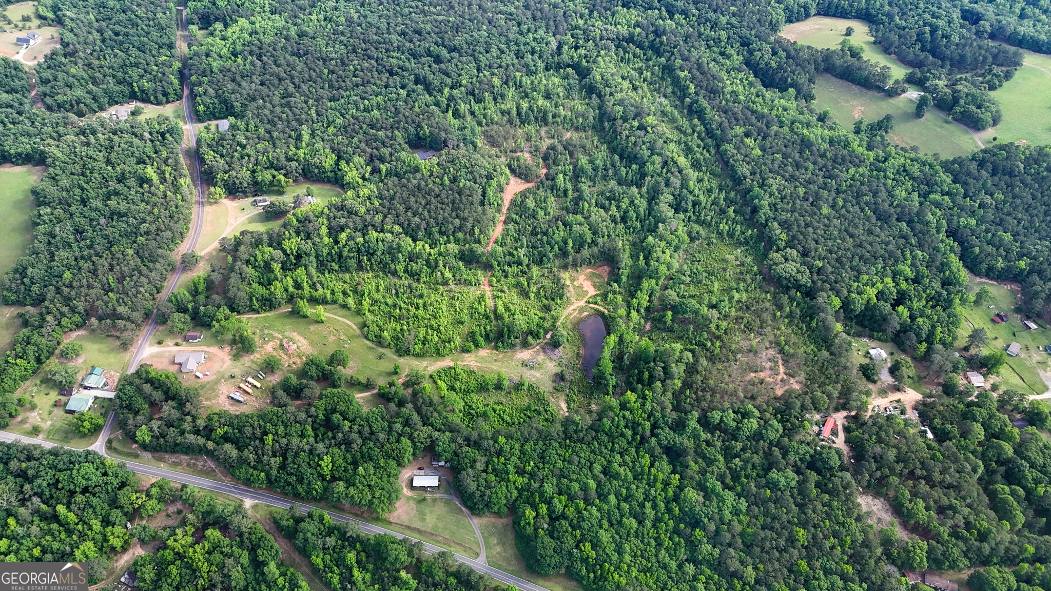 an aerial view of a house with a lush green forest