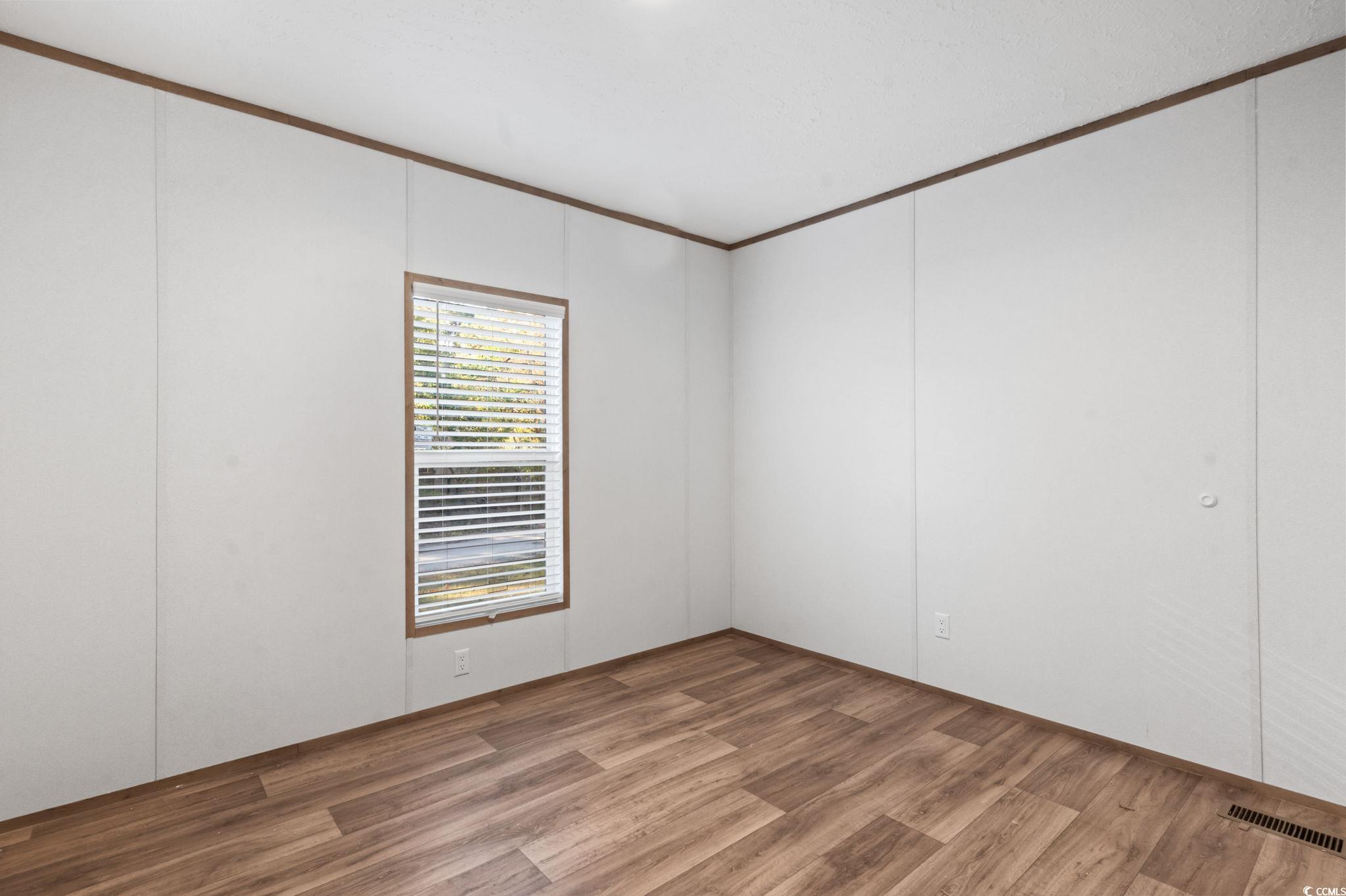 4448 Flat Bay Circle Myrtle Beach, SC 29588 - Photo 7 of 30 Empty room featuring wood finished floors and crown molding