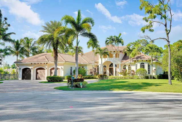 a view of a white house with a big yard and palm trees