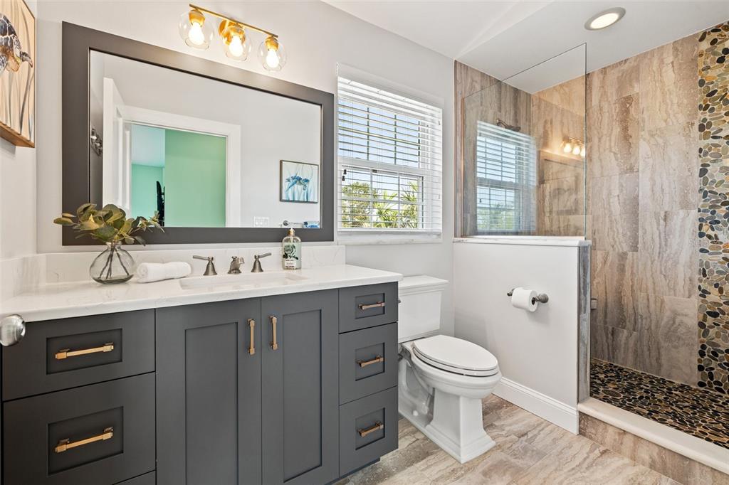 511 Windward Passage Clearwater Beach, FL 33767 - Photo 24 of 40 a spacious bathroom with a sink a toilet a large mirror and shower