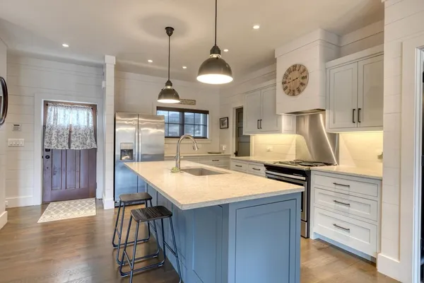a kitchen with stainless steel appliances a dining table chairs and wooden floor