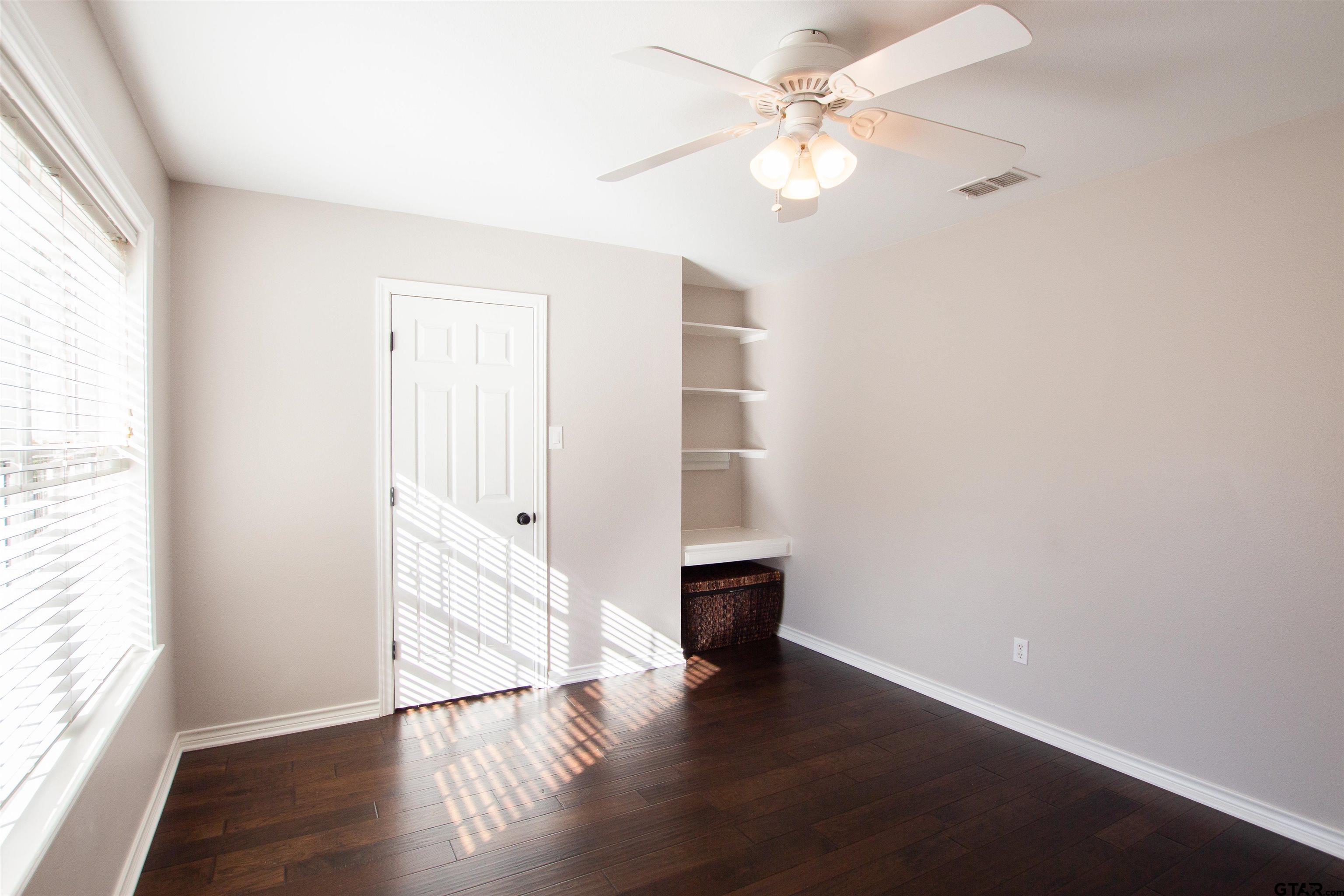 2618 Prestwick Road Jacksonville, TX 75766 - Photo 16 of 38 an empty room with wooden floor fan and windows