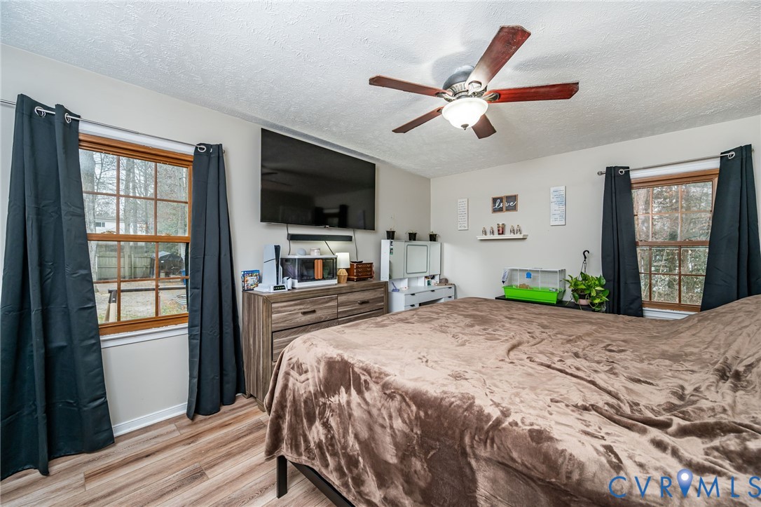 12190 Pinyon Lane Ruther Glen, VA 22546 - Photo 23 of 36 a bedroom with a large bed a flat tv screen and a window