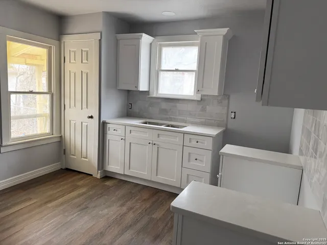 a kitchen with white cabinets and wooden floor