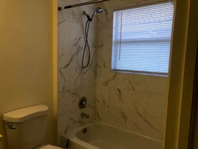a bathroom with a shower a toilet and a window