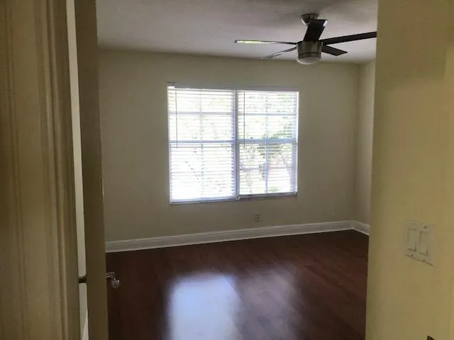 an empty room with wooden floor fan and windows