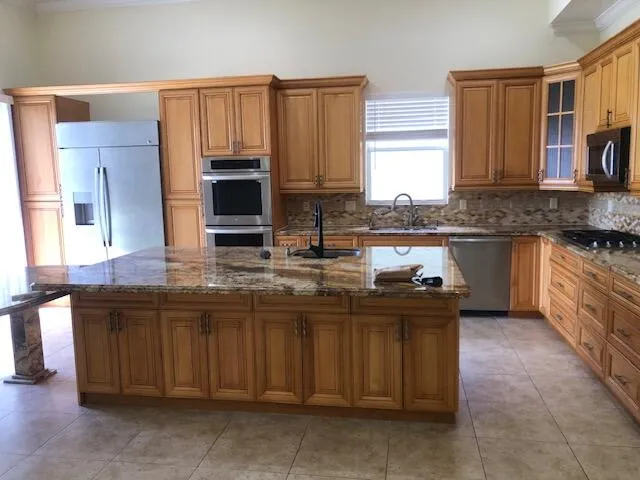 a kitchen with kitchen island granite countertop a stove top oven microwave and cabinets