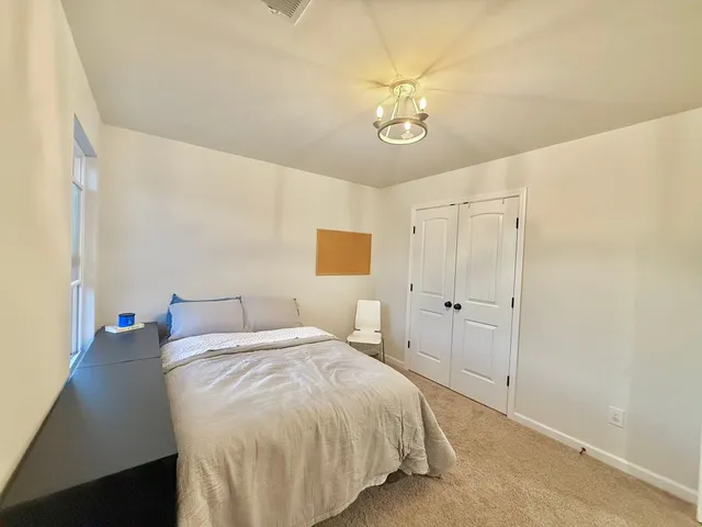 a spacious bedroom with a bed and a chandelier