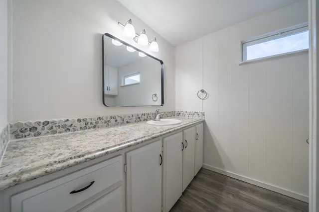 a bathroom with a granite countertop sink and a mirror