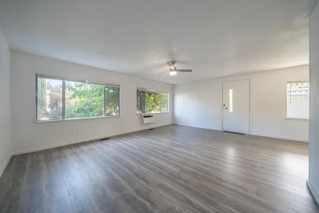 an empty room with wooden floor and windows