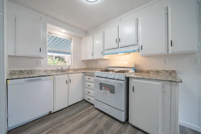 a kitchen with granite countertop white cabinets and white appliances