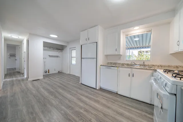 a kitchen with white cabinets and wooden floor