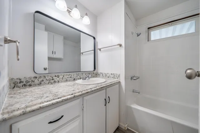 a bathroom with a granite countertop sink mirror and a bathtub