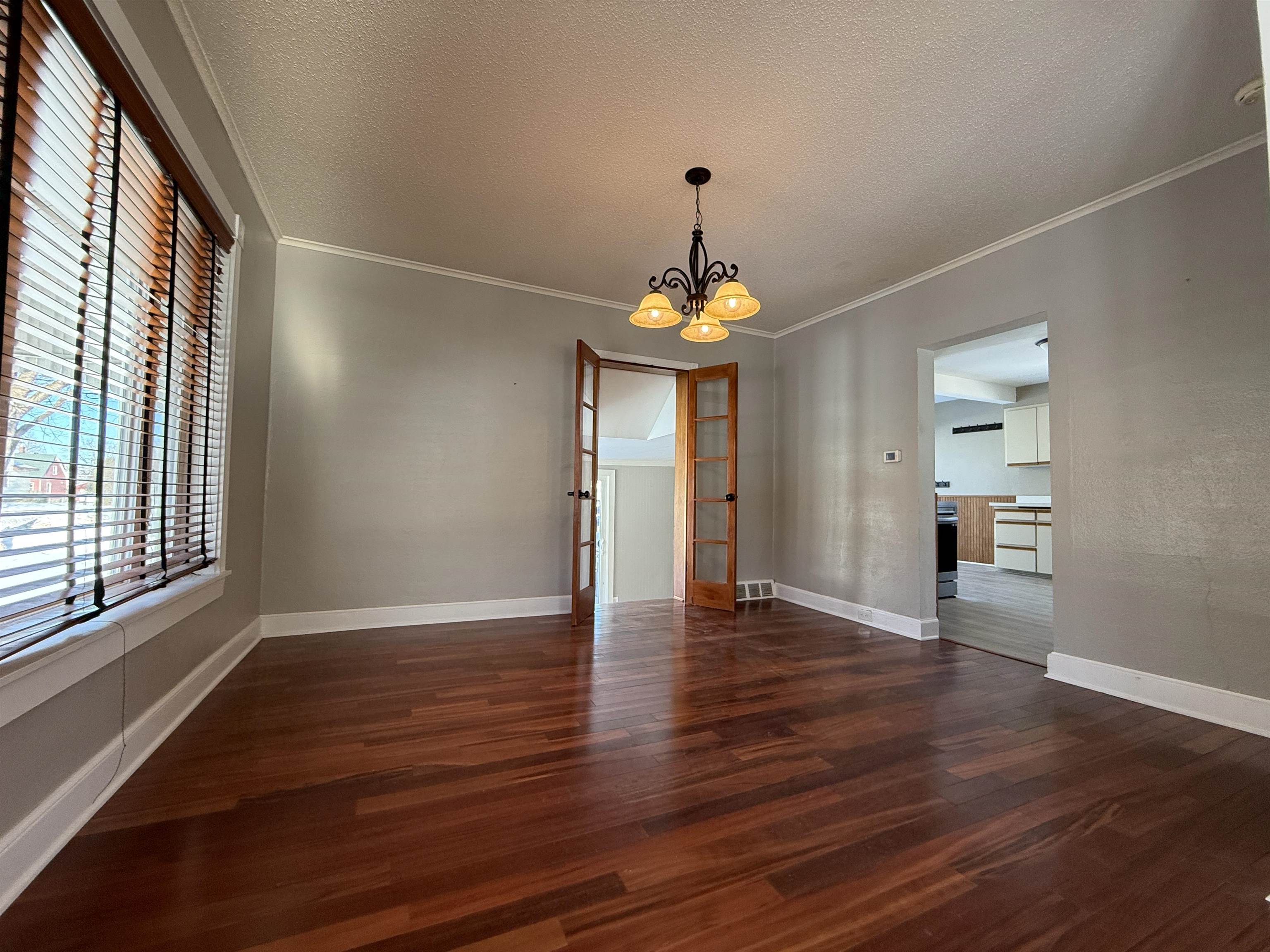 126 5th Street Northwest Chisholm, MN 55719 - Photo 10 of 35 Unfurnished dining area with a textured ceiling, a chandelier, dark wood-style floors, and ornamental molding
